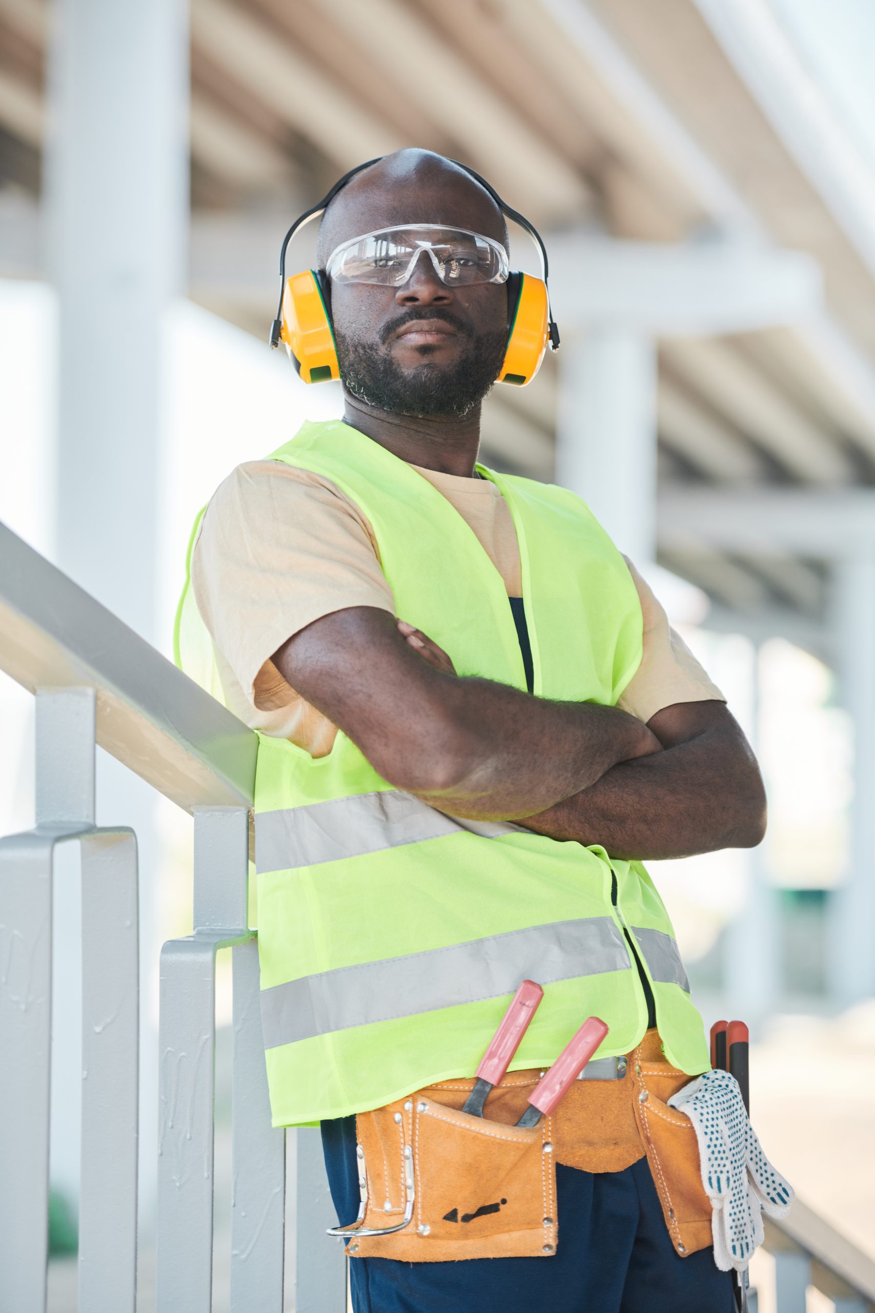 Black construction worker wearing hardhat Portrait of smiling construction worker wearing hardhat while posing against concrete wall, copy space